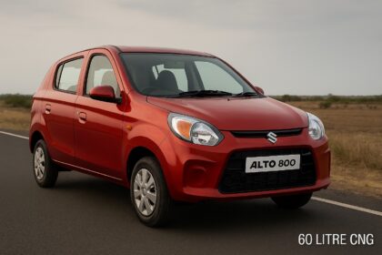 लाल रंग की Maruti Suzuki Alto 800 दो लेन वाली सड़क पर खड़ी है, बैकग्राउंड में खुला मैदान और बादलों से ढका आसमान नजर आ रहा है।